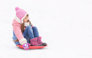 Joyful girl having fun and sledding on snow